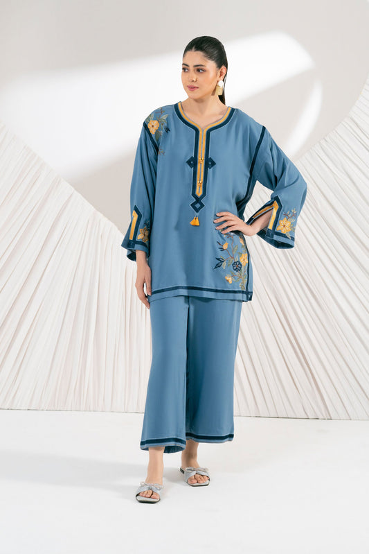 Woman wearing a blue embroidered outfit on a white background