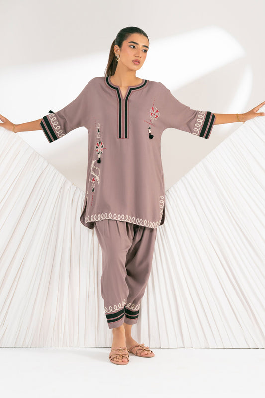 Woman wearing a mauve traditional outfit with black embroidery on a white background