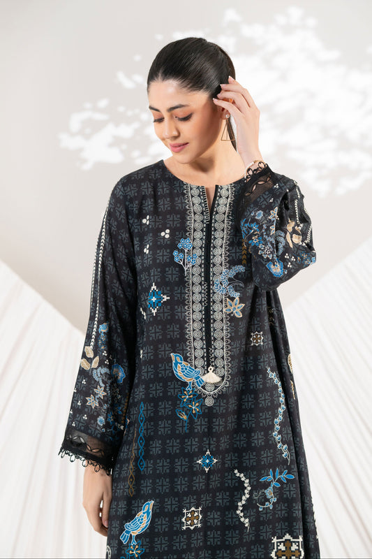 Woman wearing a black embroidered dress with floral patterns on a white background