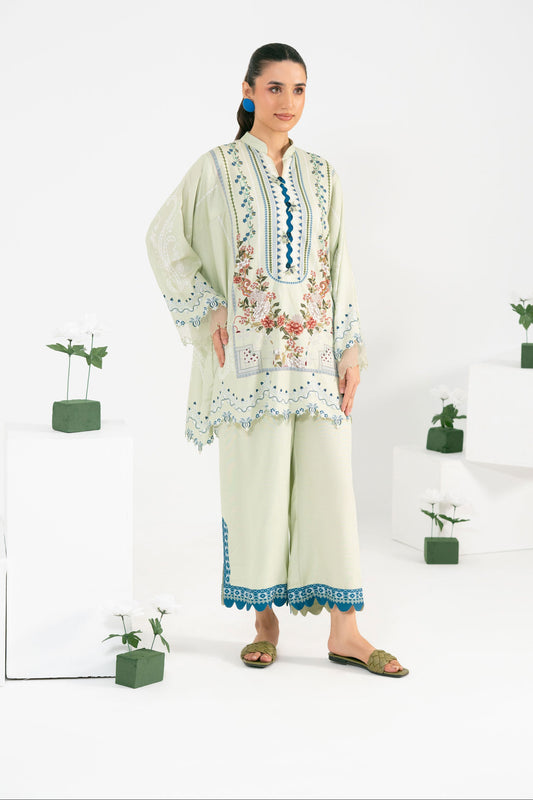 Woman wearing a light green embroidered outfit with a white background