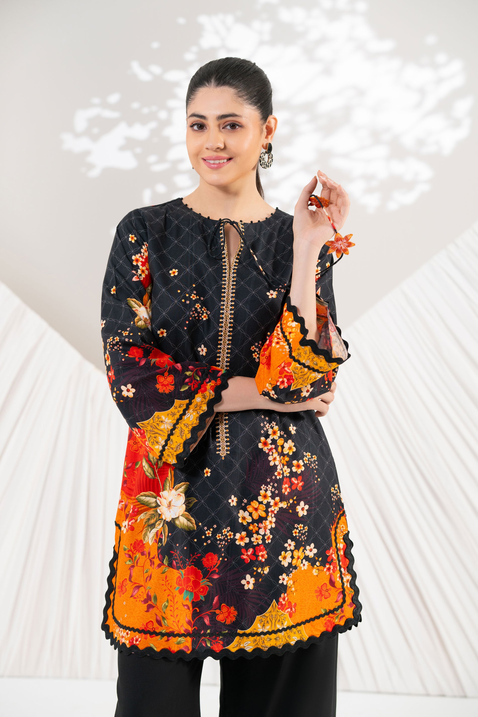 Woman wearing a black and orange floral dress with a white background