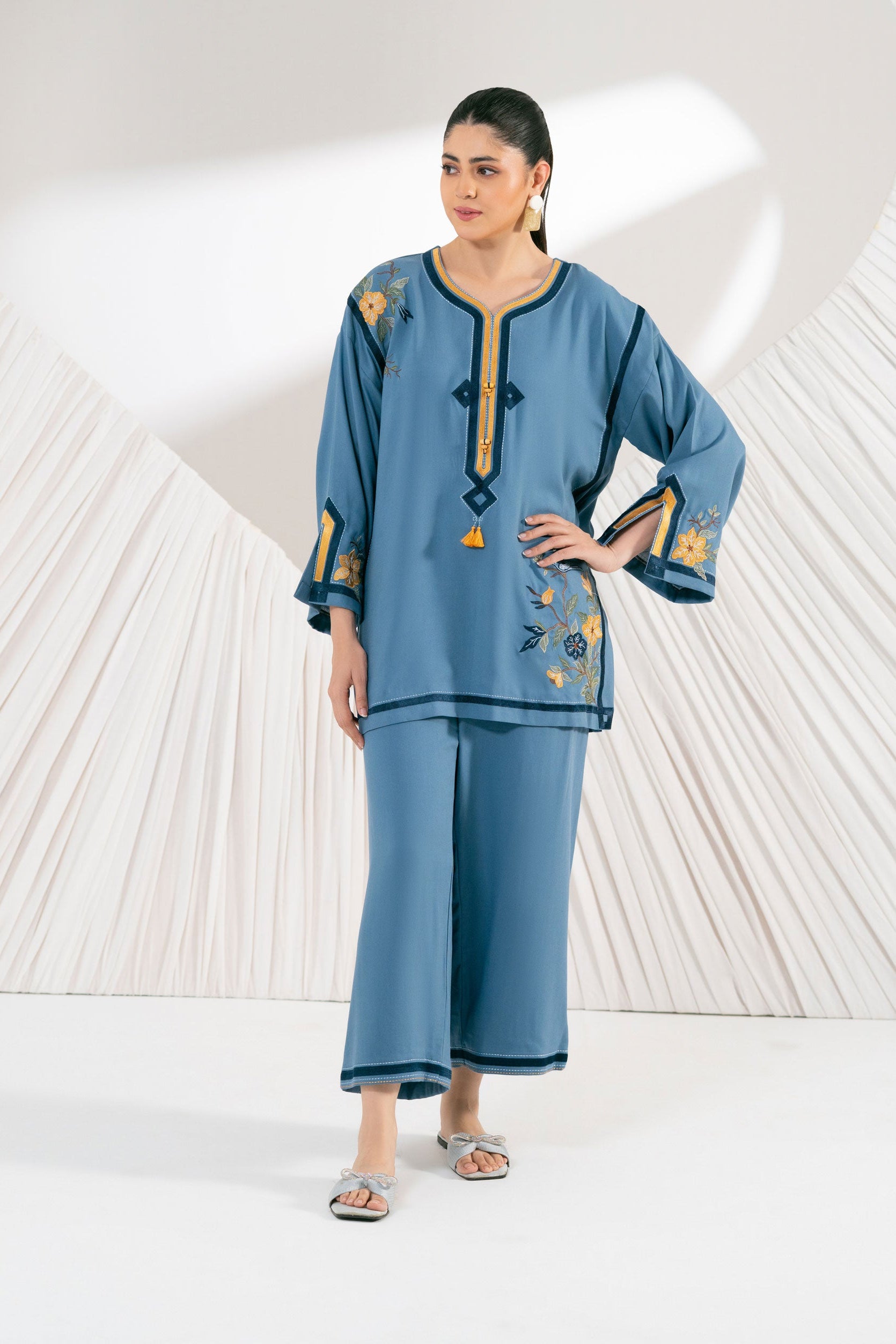 Woman wearing a blue embroidered outfit on a white background