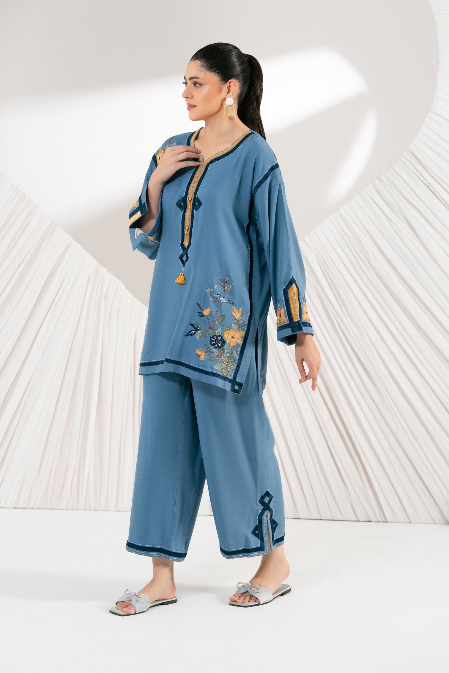 Woman wearing a blue embroidered outfit with a white background