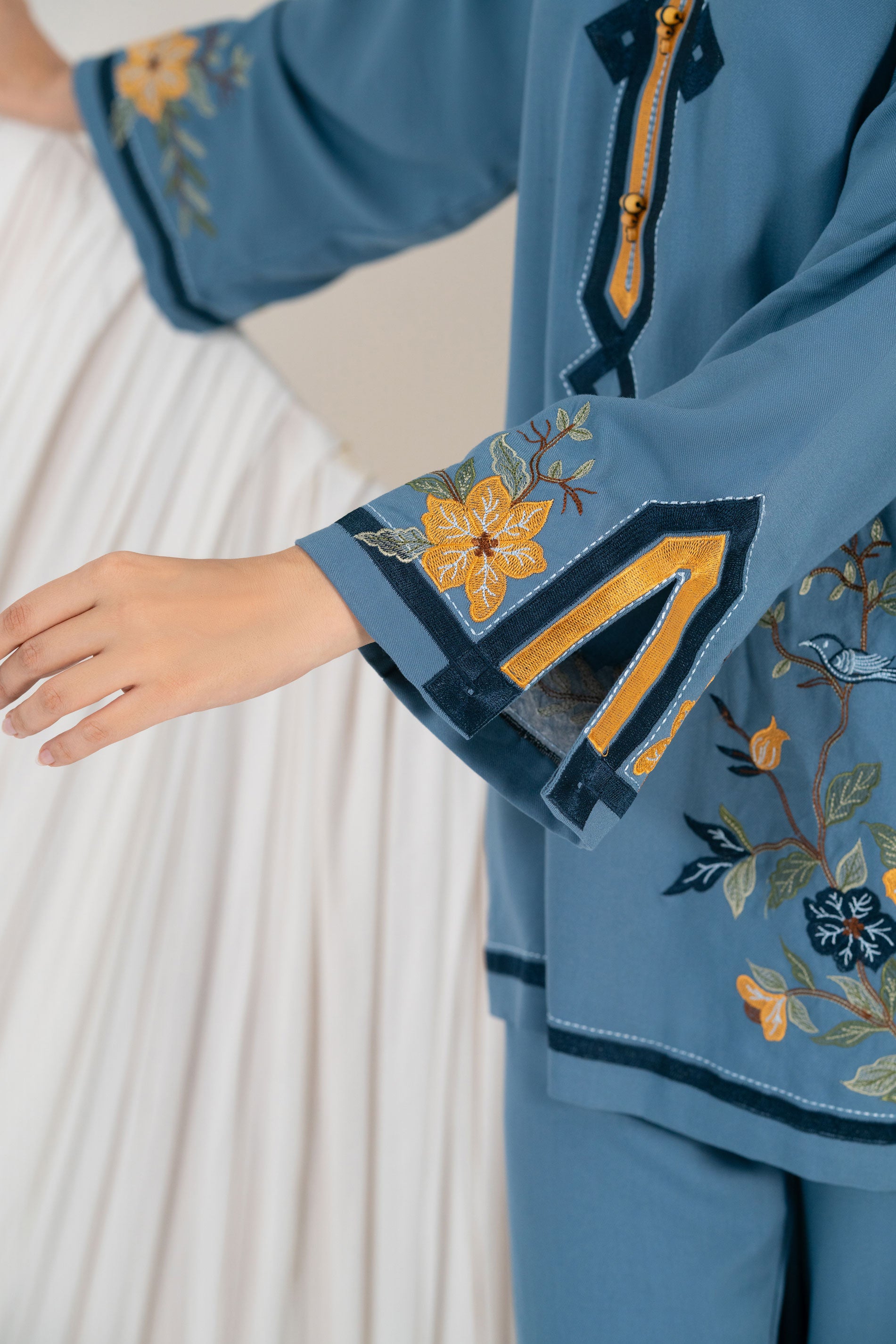 Blue embroidered outfit with yellow accents on a white background