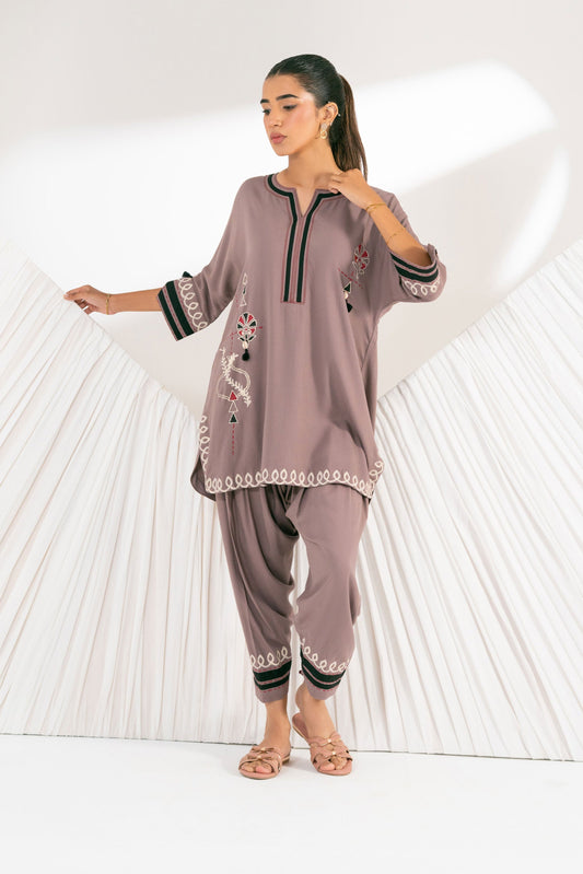 Woman wearing a traditional outfit with intricate designs in front of a heart-shaped light sculpture.