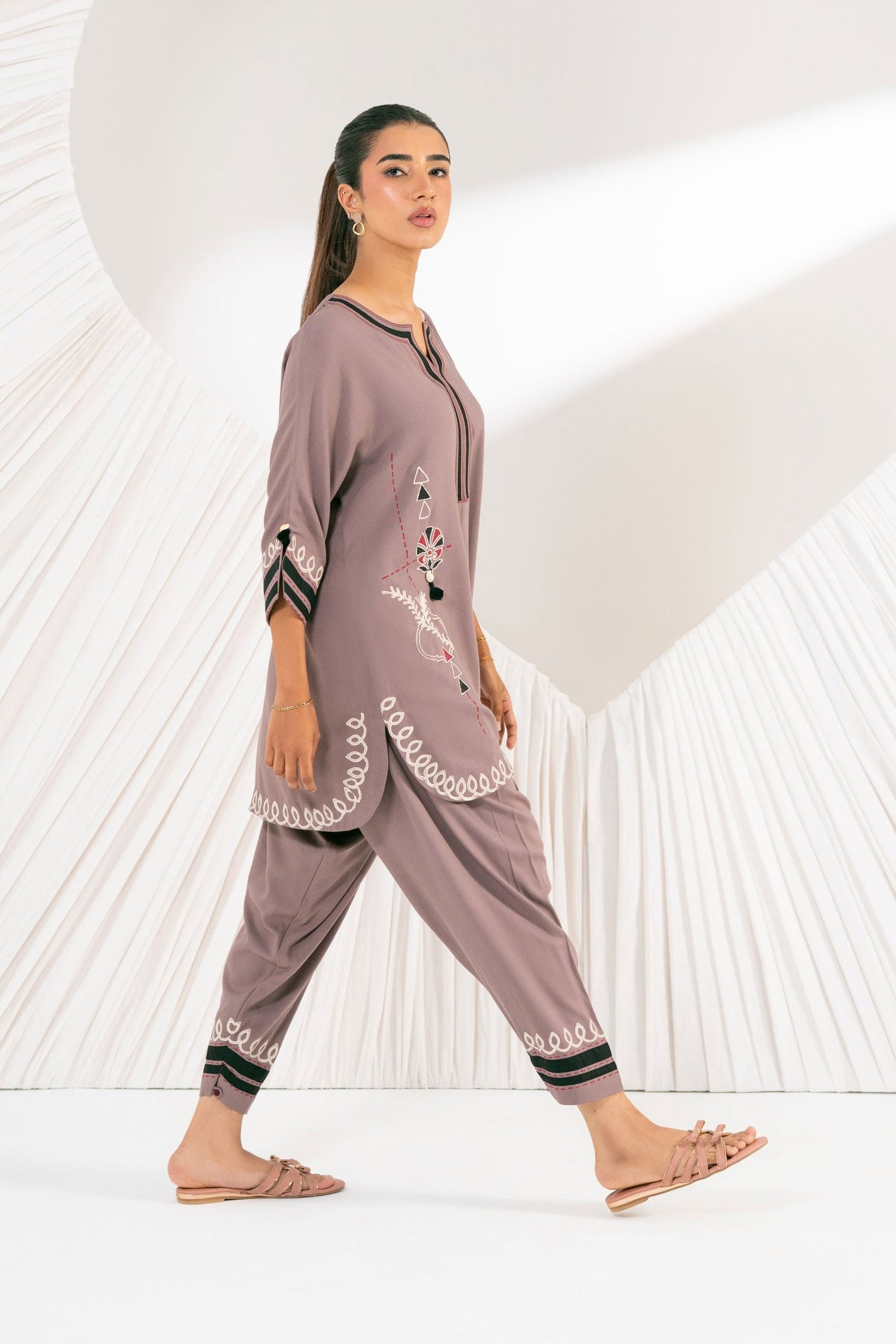 Woman wearing a matching outfit with a long top and pants on a white background