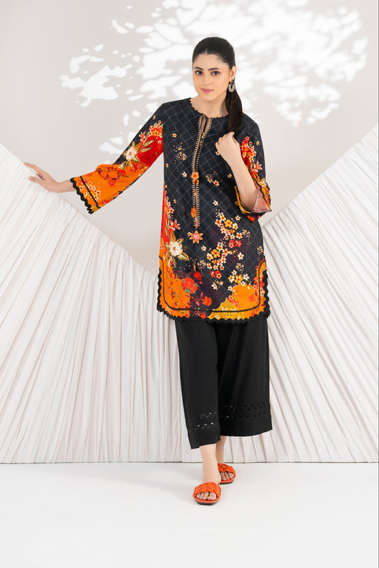 Woman wearing a black and orange floral dress with black pants against a white background