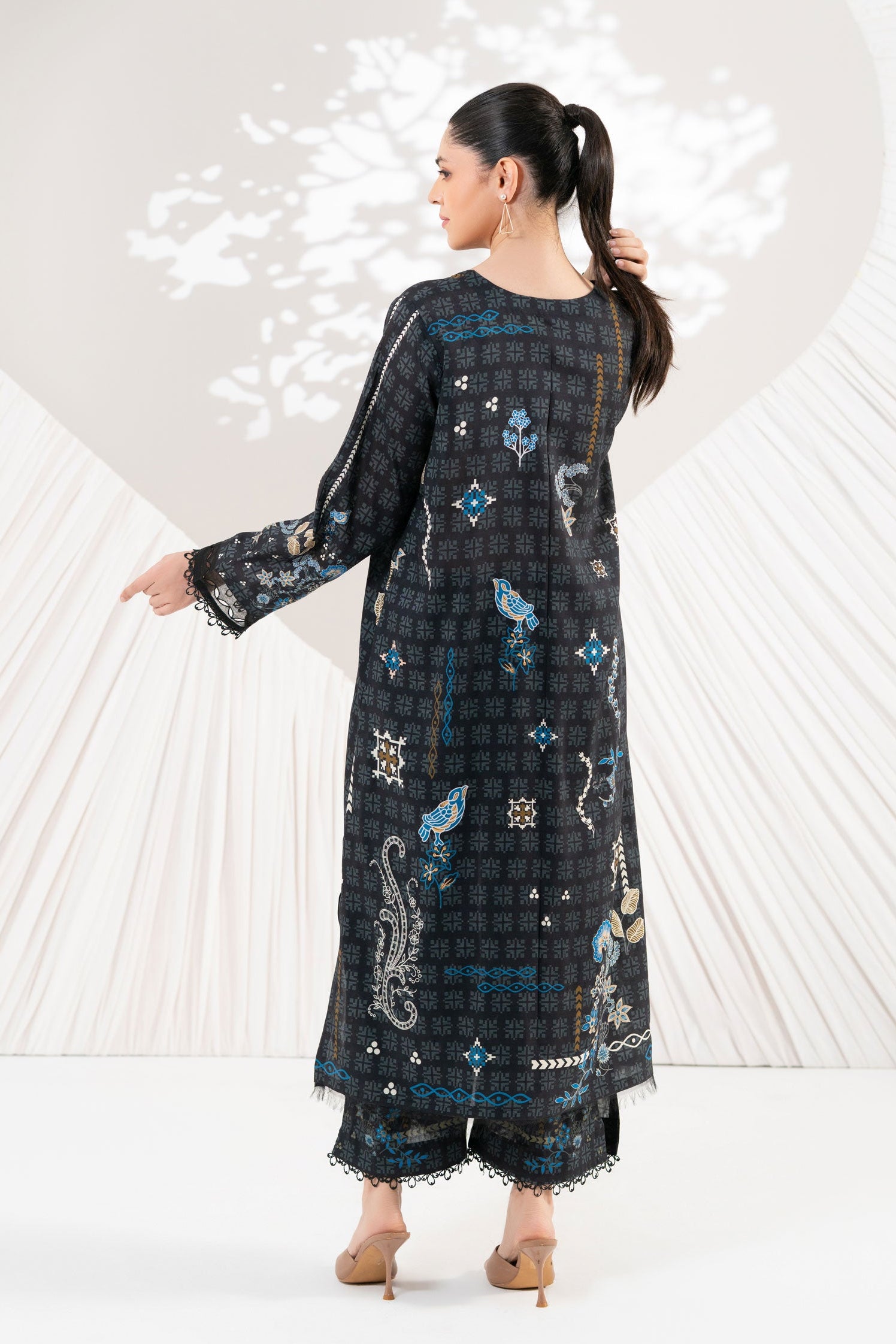 Woman wearing a long, dark-colored dress with floral patterns against a white background