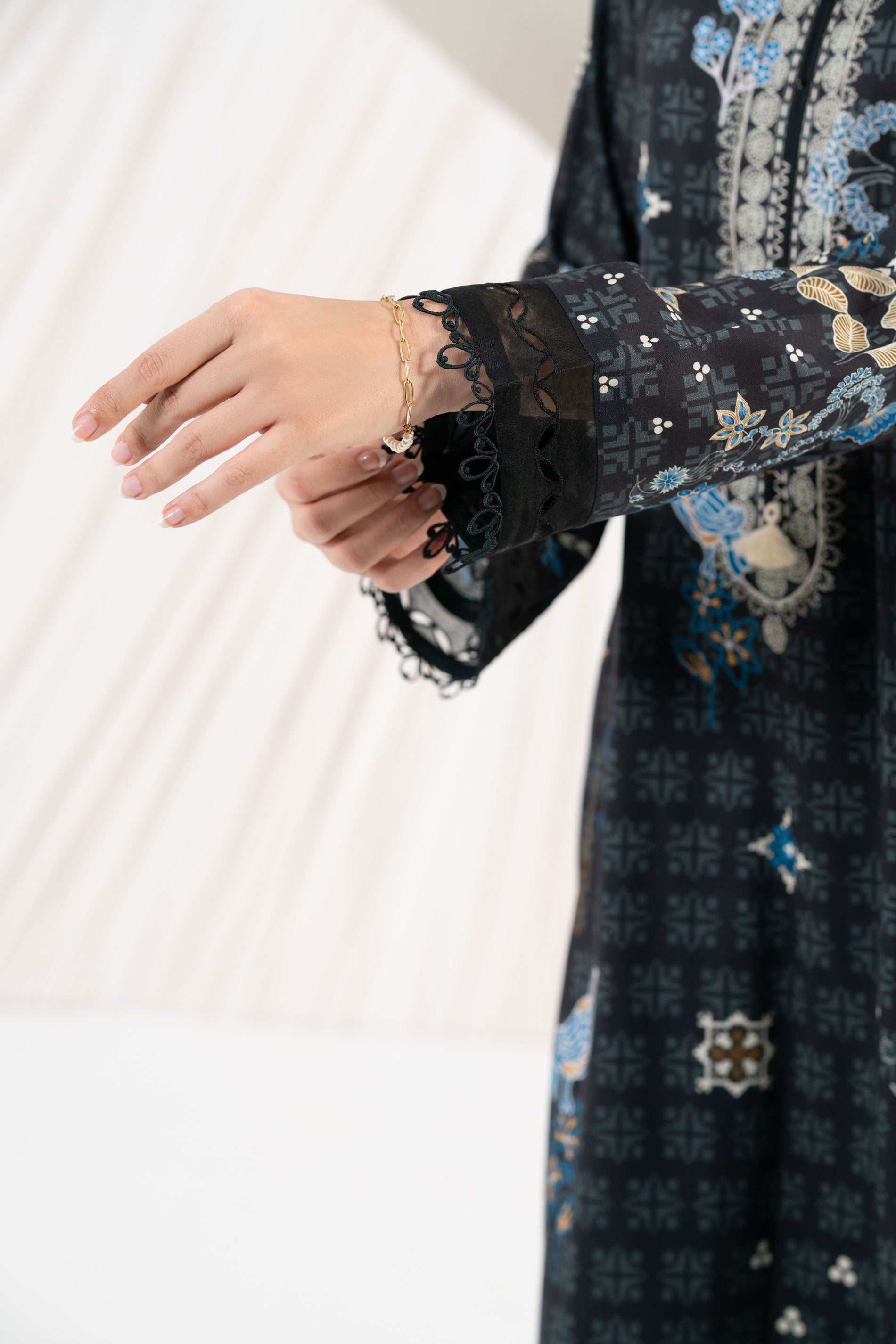 Close-up of a person wearing a dark patterned garment with lace sleeves.