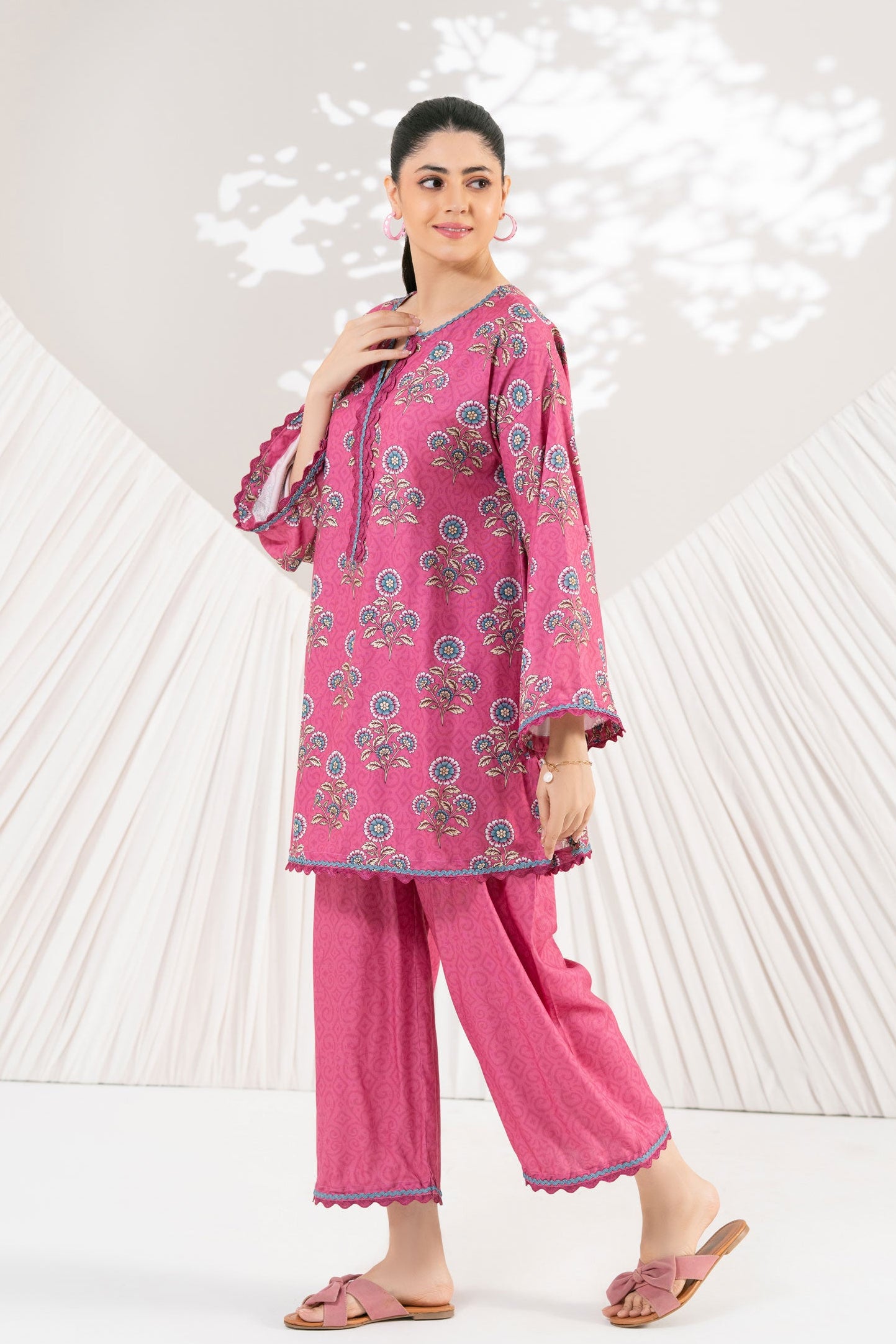 Woman wearing a pink traditional outfit with floral patterns against a white background