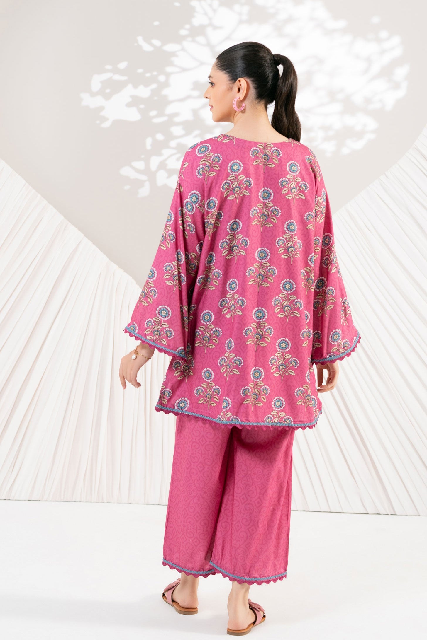 Woman wearing a pink traditional outfit with floral patterns against a white background