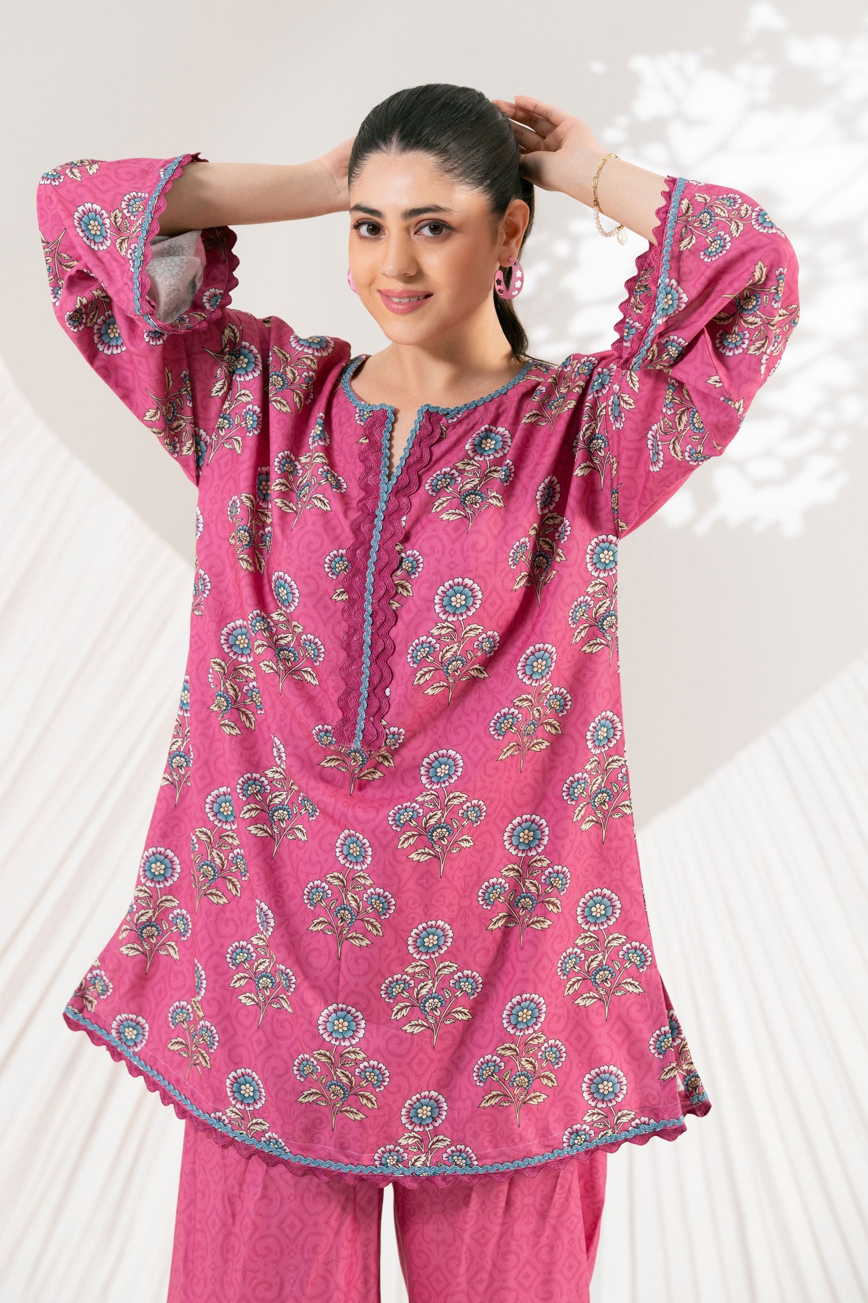 Woman wearing a pink traditional outfit with floral patterns on a white background