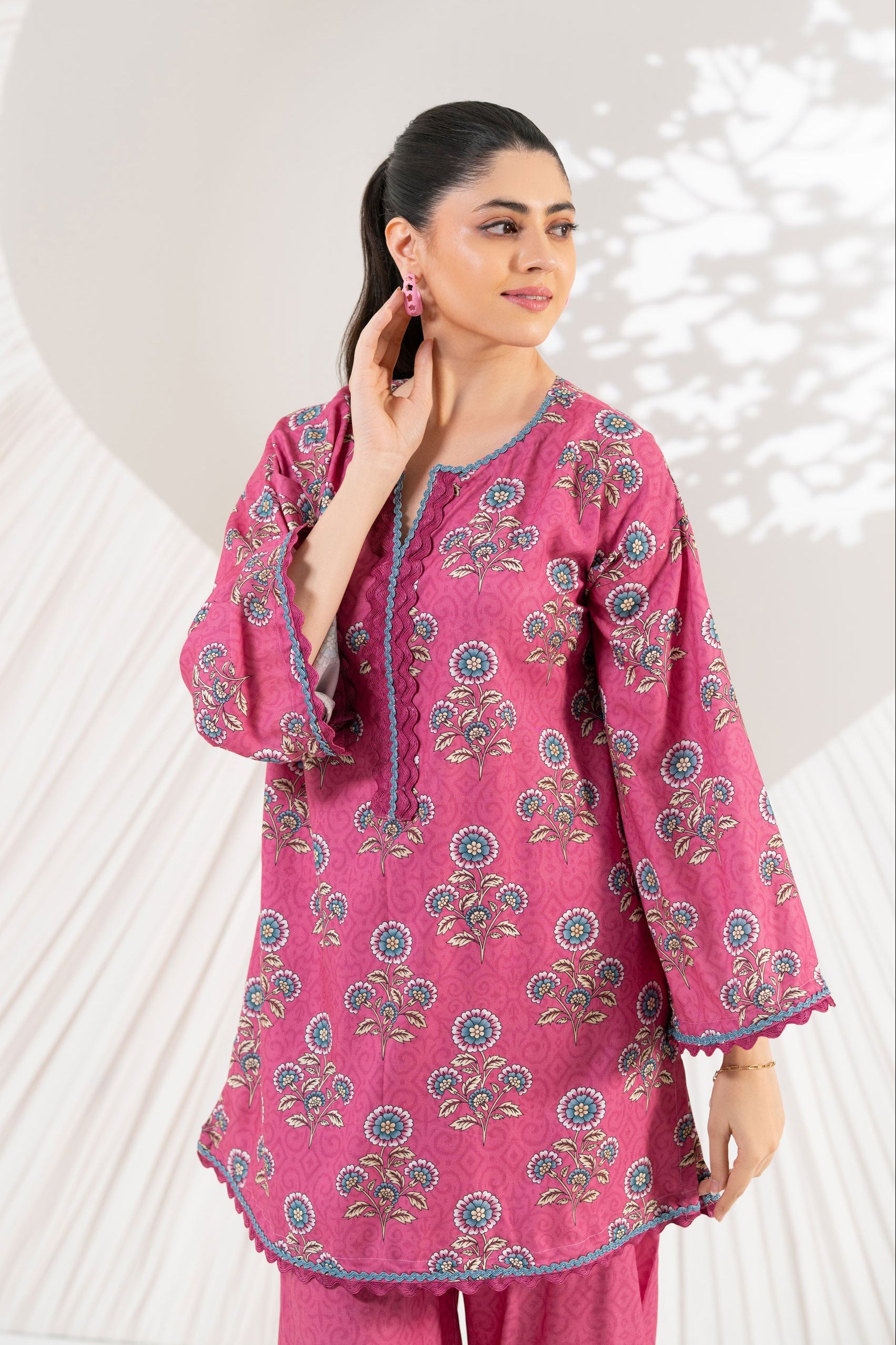 Woman wearing a pink floral outfit against a white background