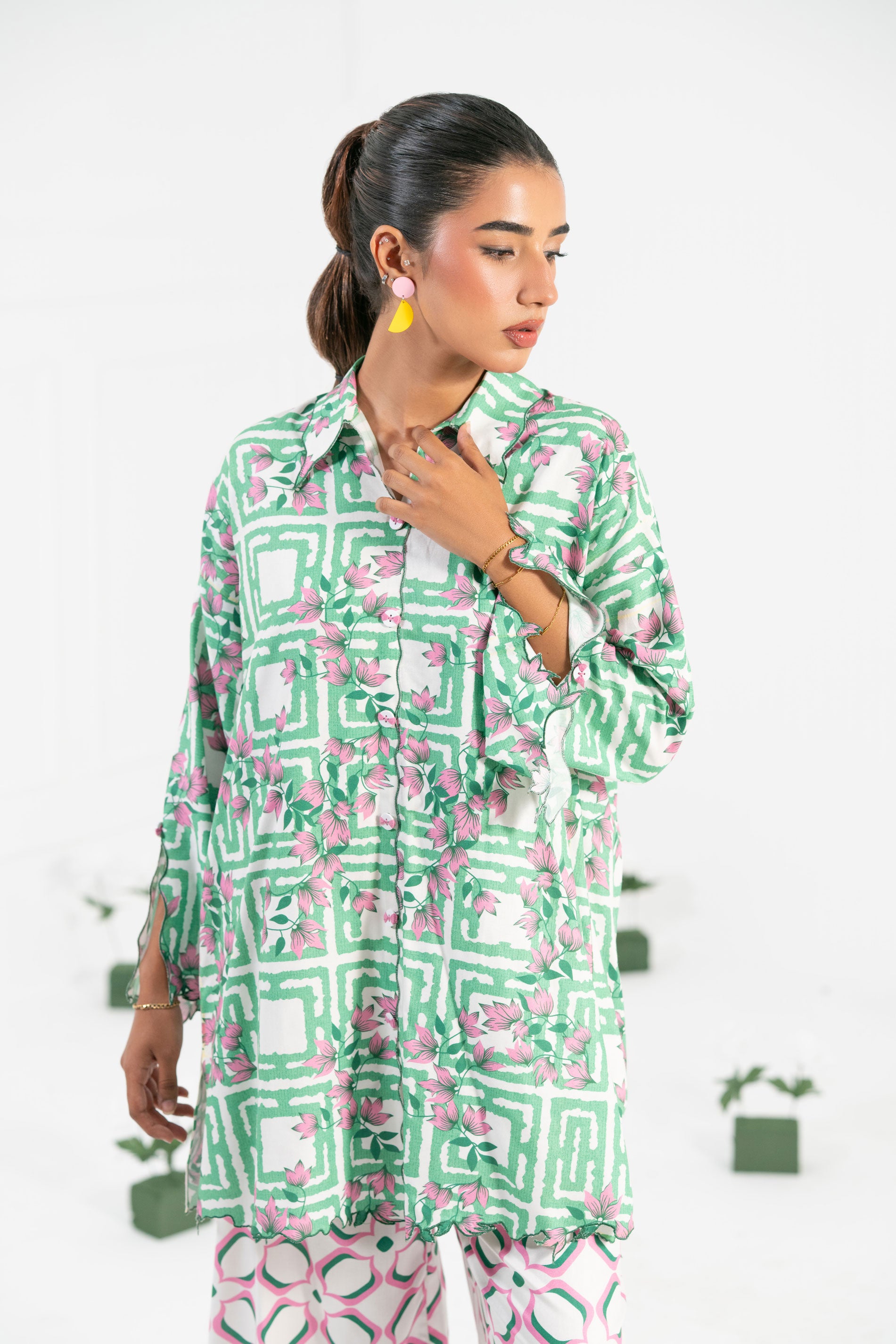 Woman wearing a green and pink patterned outfit on a white background