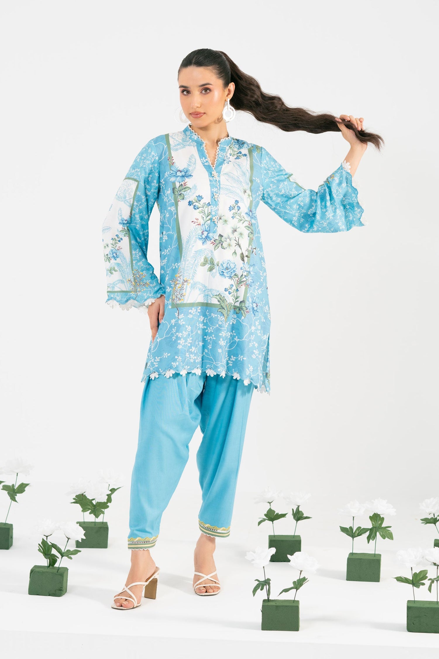 Woman in a light blue floral outfit with potted plants on a white background