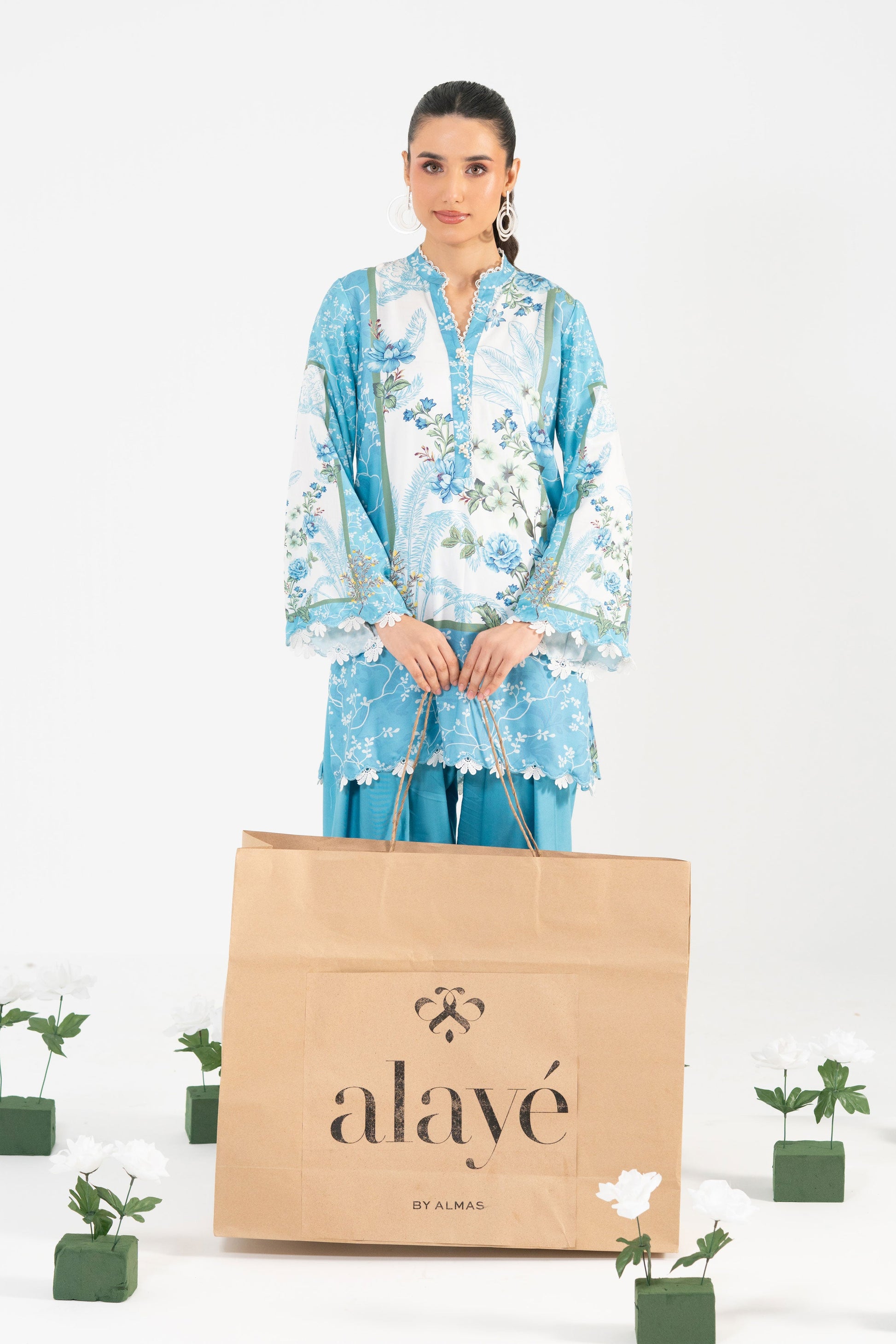 Woman holding a 'alayé' bag with plants in the background