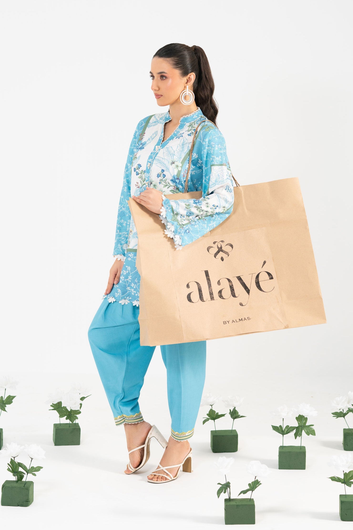 Woman holding a 'alayé' bag with plants on a white background