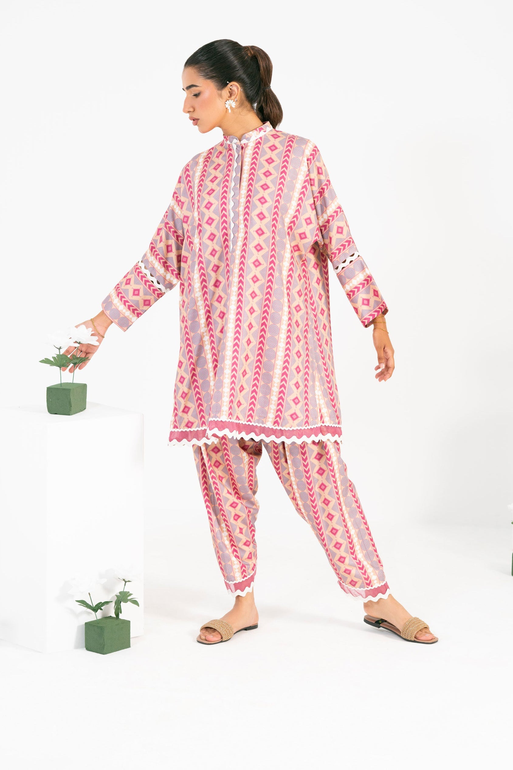 Woman wearing a pink and white patterned pajama set on a white background