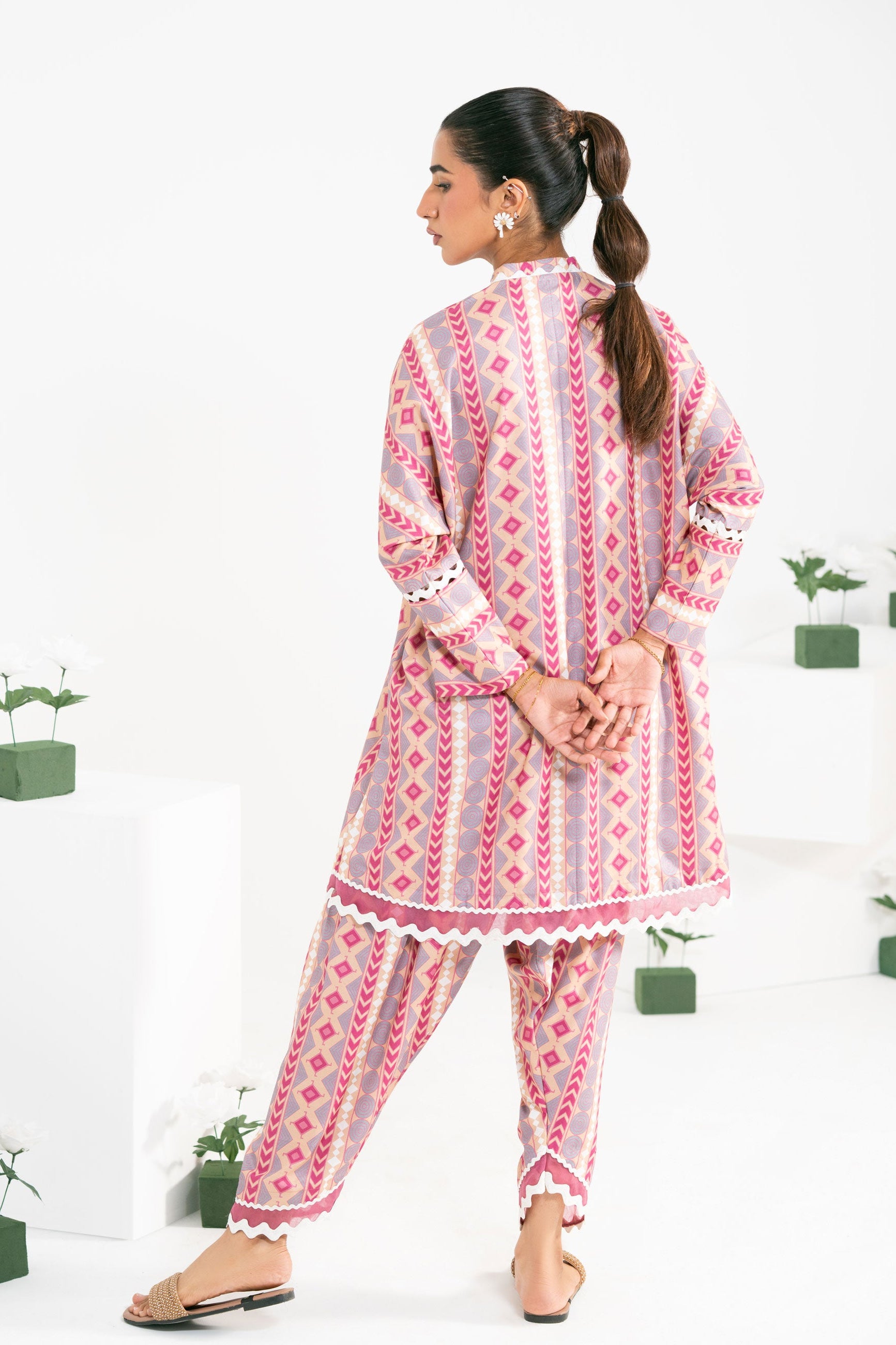 Woman wearing a pink and white patterned outfit on a white background