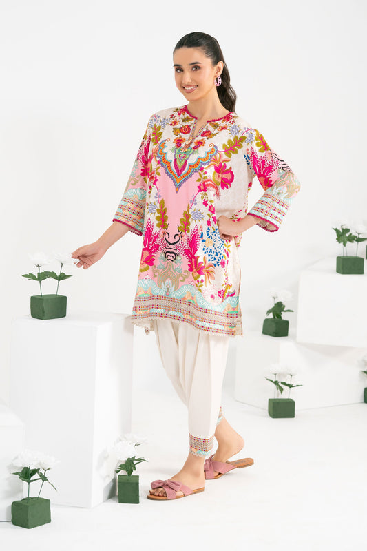 Woman wearing a colorful floral dress with white pants against a white background 