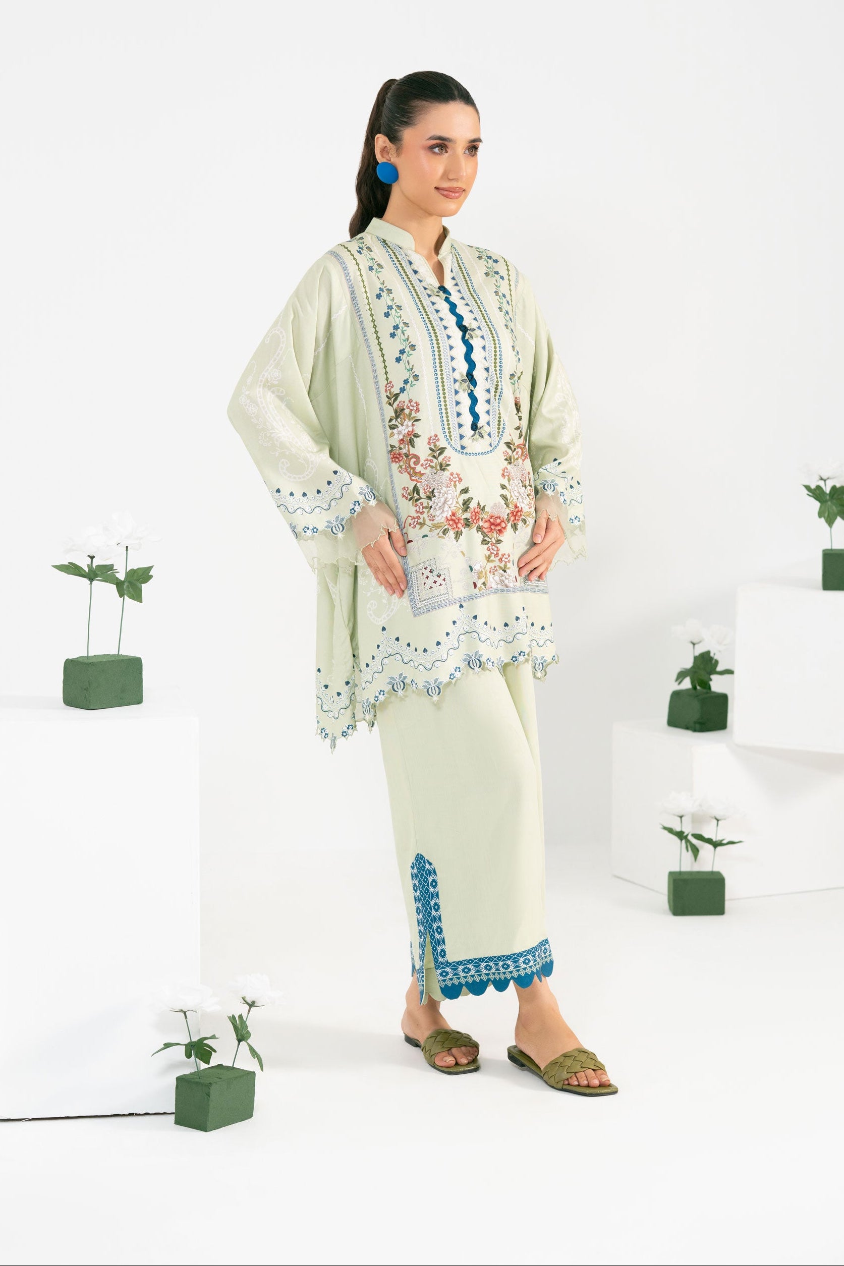 Woman wearing a light green embroidered outfit with a white background