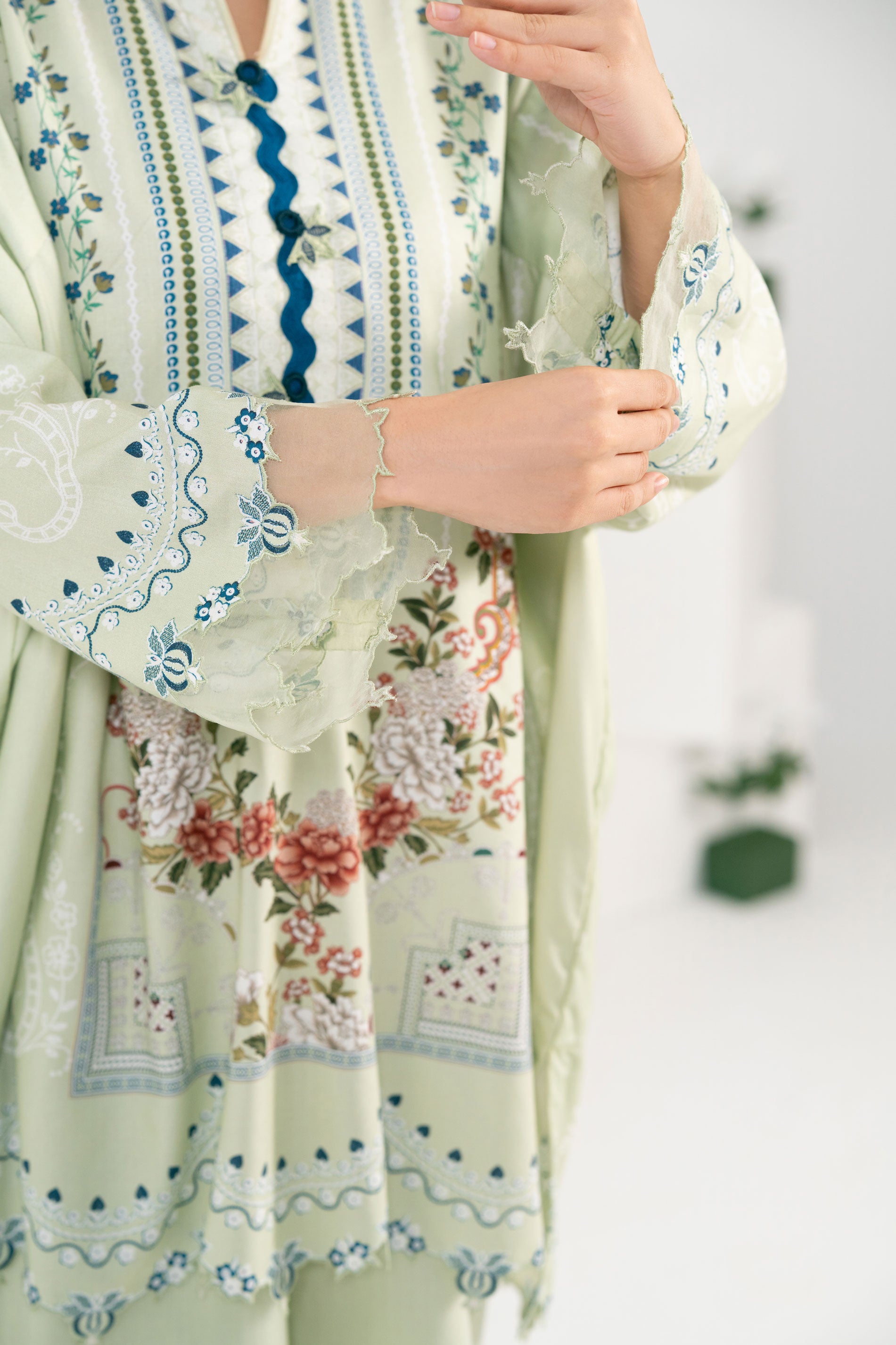 Light green dress with floral and geometric patterns on a blurred background
